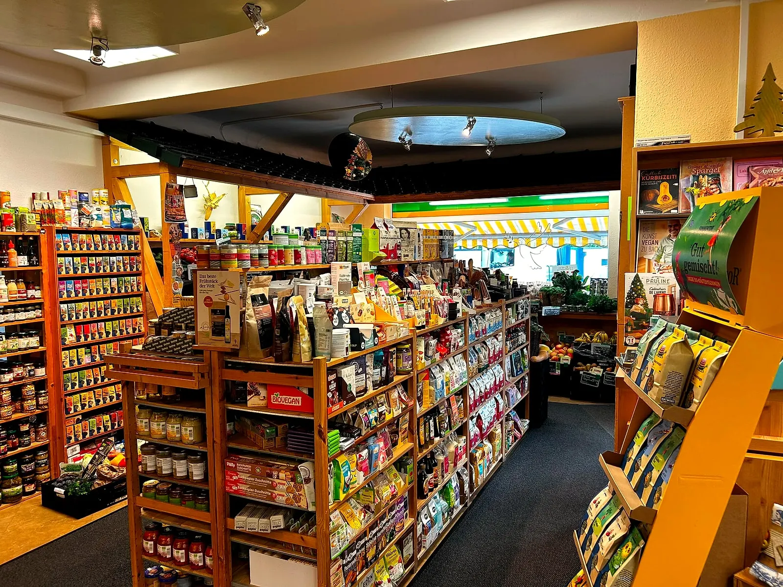 Eingangsbereich des Biolino Naturmarkts mit Holzregalen voller Lebensmittel, im Hintergrund das Schaufenster